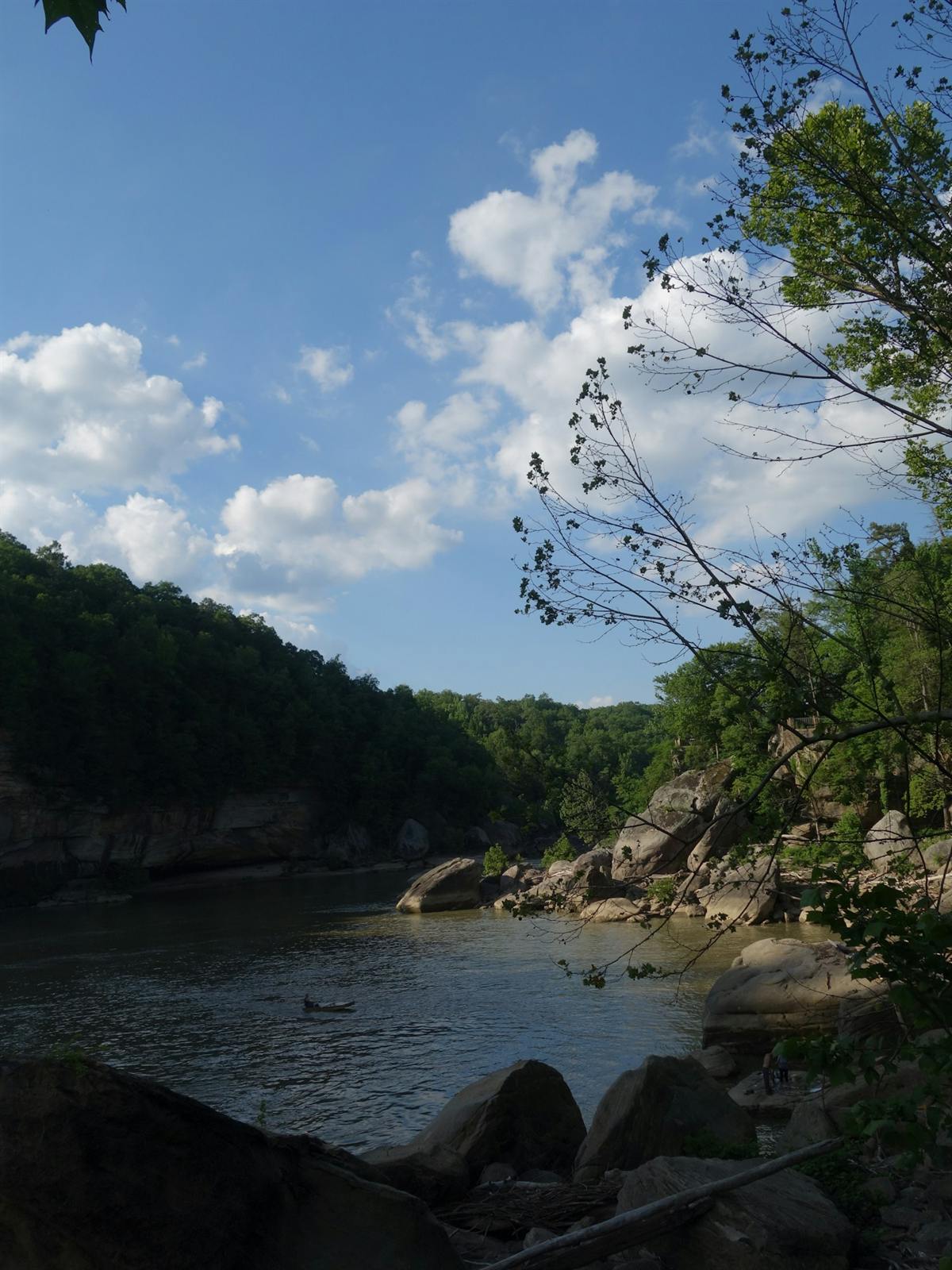 A kayaker paddling a calm river beneath sandstone cliffs
