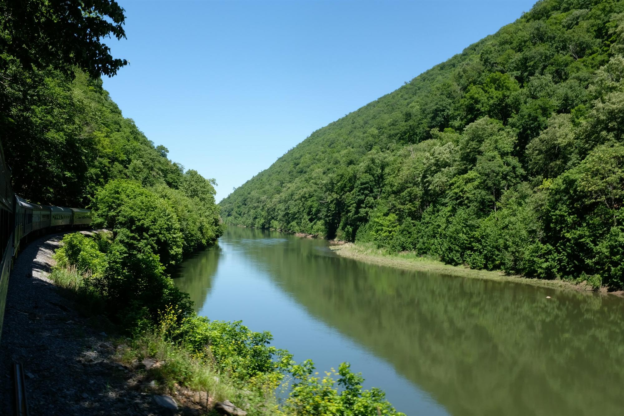 A river winding through a lush green valley between forested Appalachian ridges